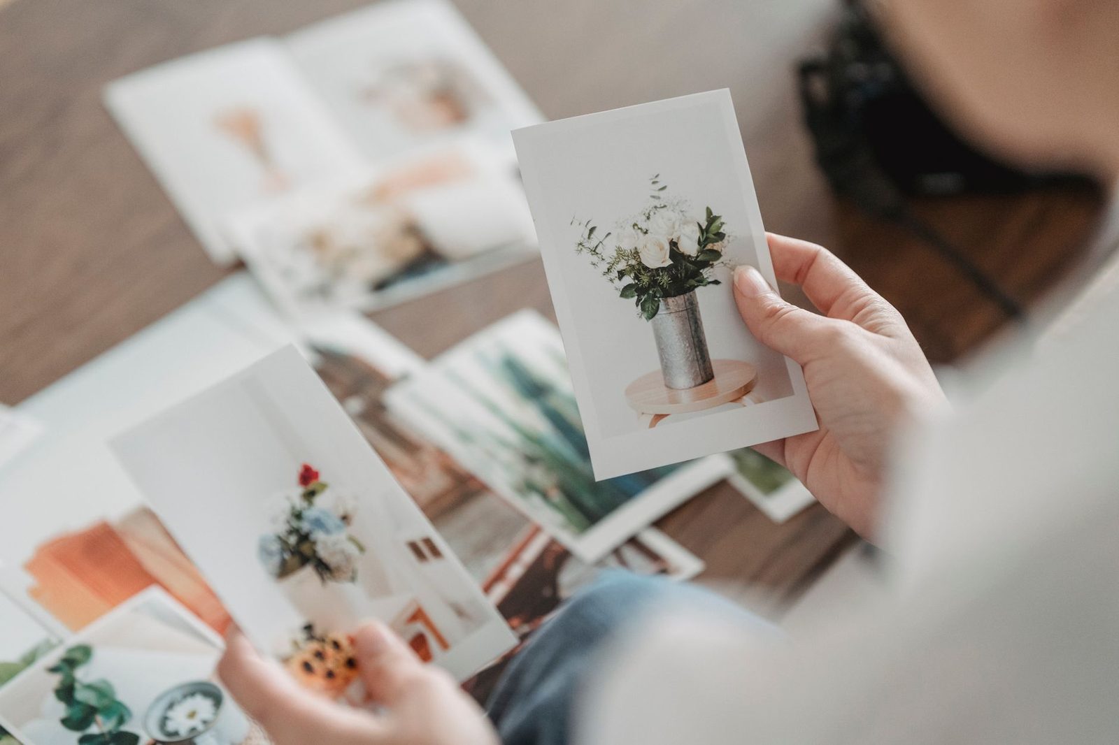 Florista seleccionando fotografías de ceremonias y centros de mesa sobre una mesa de trabajo